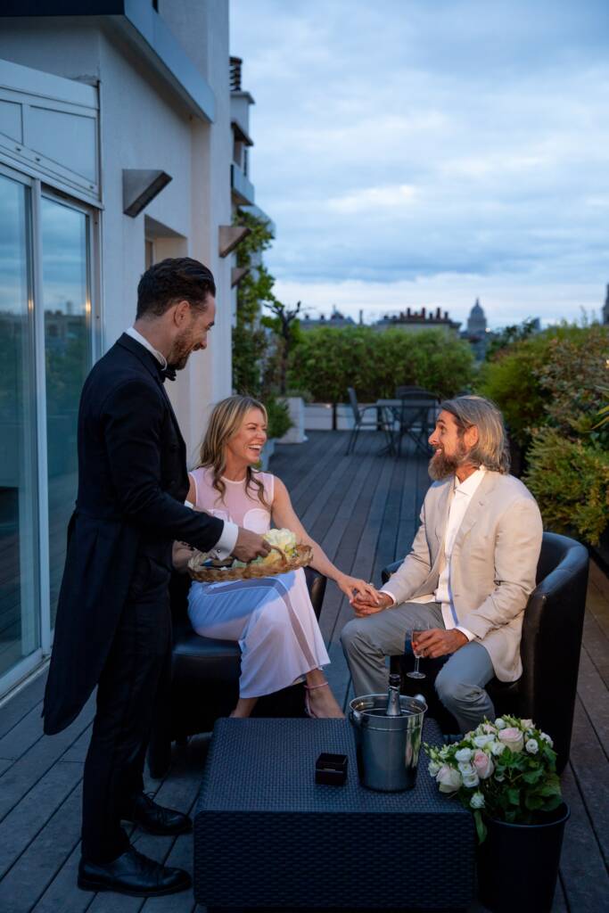 Man approaching partner seated on outdoor lounge furniture during upscale luxury event organized by Paris proposal agency